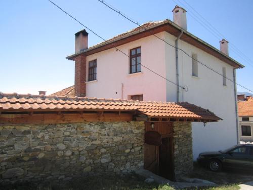 a white house with a stone wall and a car at Guest House Popov in Marchevo