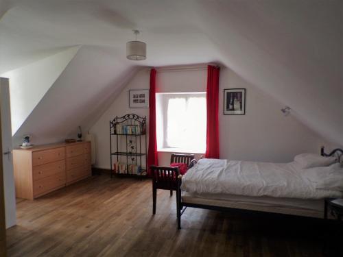 - une chambre avec un lit et une fenêtre avec des rideaux rouges dans l'établissement Ker Jerome - Traditional Stone Breton Cottage near to Dinan, à Trélivan