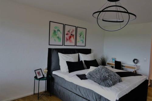 a bedroom with a black and white bed and a chandelier at Modernes Apartment mit Traumhaftem Blick ins Grüne in Bräunlingen