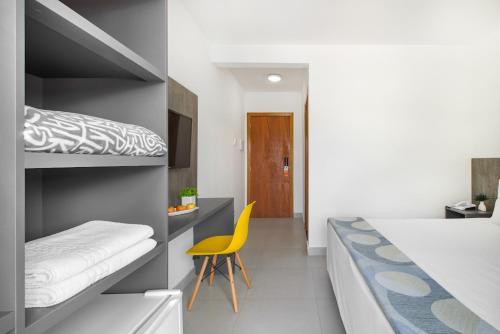 ein Schlafzimmer mit einem Etagenbett und einem gelben Stuhl in der Unterkunft Hotel Cajueiro Guarujá in Guarujá