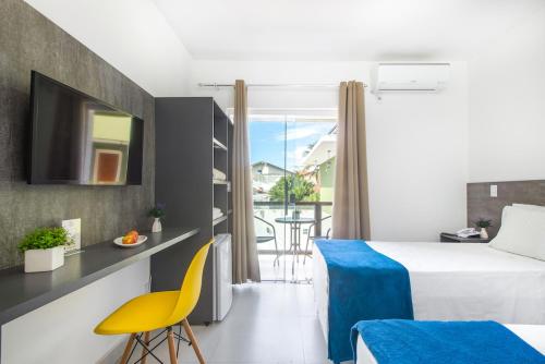 a hotel room with a bed and a yellow chair at Hotel Cajueiro Guarujá in Guarujá