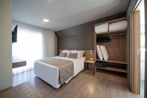 een slaapkamer met een groot wit bed en een groot raam bij Golden Laghetto Resort Gramado in Gramado