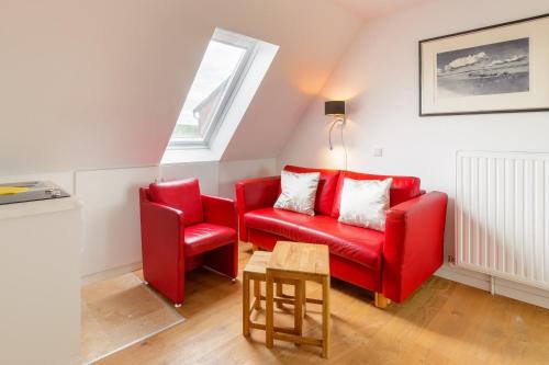 a living room with a red couch and a chair at Strand-Muscheln in Dagebüll