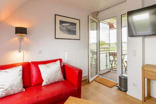 a red couch in a living room with a flat screen tv at Strand-Muscheln in Dagebüll