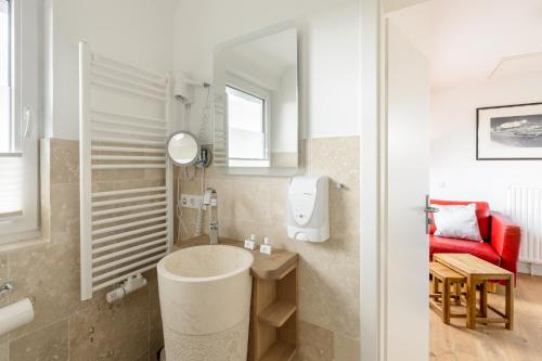 a bathroom with a sink and a red couch at Strand-Muscheln in Dagebüll
