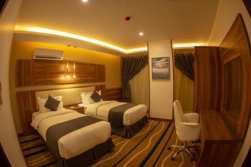 a hotel room with two beds and a chair at جولدن نيو-Golden New in Jazan