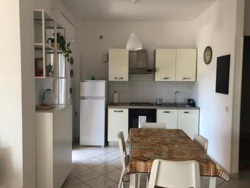 eine Küche mit weißen Geräten sowie einem Tisch und Stühlen in der Unterkunft La Casa del Sole in Santa Marinella