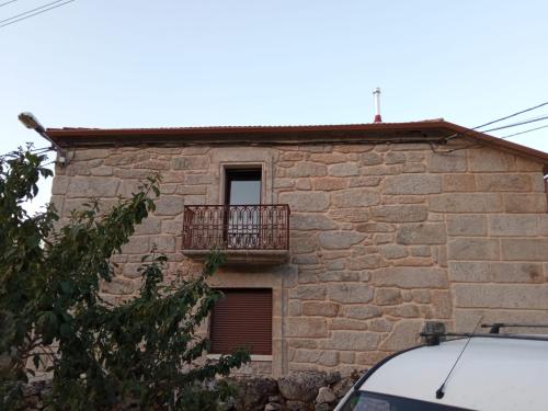 a stone house with a balcony on the side of it at Casa da Eira in Lobios