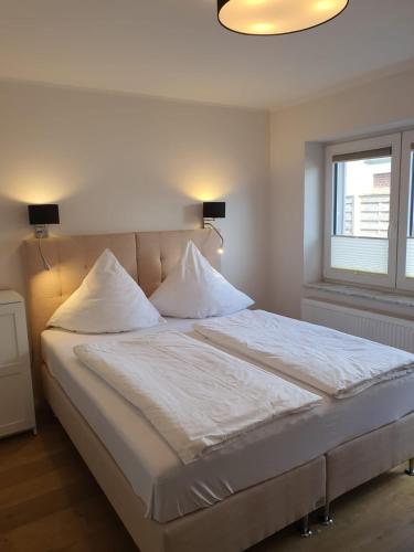 a bedroom with a bed with white sheets and a window at Nordsee-Pension Dagebüll in Dagebüll