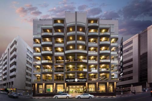 a tall building with cars parked in front of it at Savoy Central Hotel Apartments in Dubai