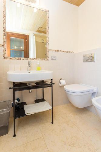 a bathroom with a sink and a toilet and a mirror at Antico Casale Tiravento in Passignano sul Trasimeno