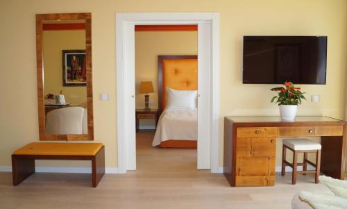 a room with a bedroom with a bed and a television at Hotel Greif in Lignano Sabbiadoro