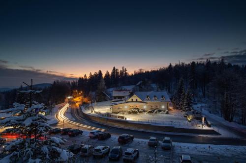 a winter night with cars parked in a parking lot at Karczma Kubalonka in Istebna