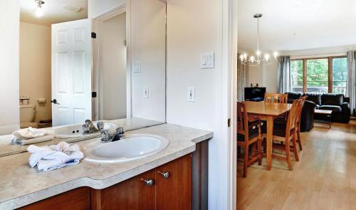 a bathroom with a sink and a mirror and a dining room at Chalets Alpins- 05 Chemin Alpin in Stoneham