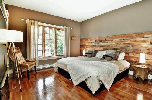 a bedroom with a bed and a wooden wall at Chalets Alpins - 56 Chemin des Skieurs in Stoneham