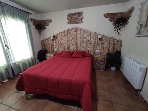 a bedroom with a large bed with a red blanket at Los Alisos Casa Rural in Guadalix de la Sierra