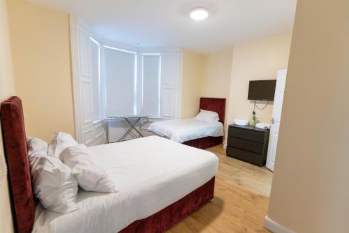 a hotel room with two beds and a television at Newcastle City Apartment All En-Suite in Elswick