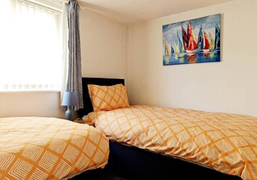 a bedroom with two beds and a painting of sailboats at Cosy little cottage in Deiniolen near Llanberis in Caernarfon