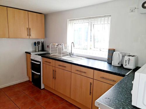 a kitchen with wooden cabinets and a sink and a window at Cosy little cottage in Deiniolen near Llanberis in Caernarfon