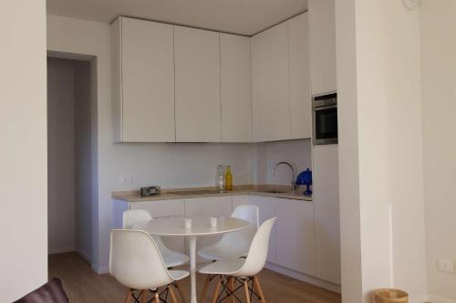 a kitchen with white cabinets and a white table and chairs at Dame di Toscana in Lastra a Signa