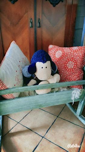 a stuffed animal sitting on a bench with pillows at Karczma Kubalonka in Istebna