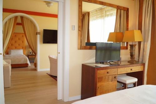 a bedroom with a television on a dresser with a mirror at Hotel Greif in Lignano Sabbiadoro