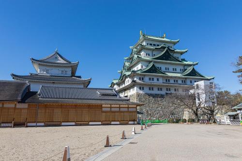 two tall buildings next to a courtyard in a city at Smile Hotel Nagoya Sakae in Nagoya