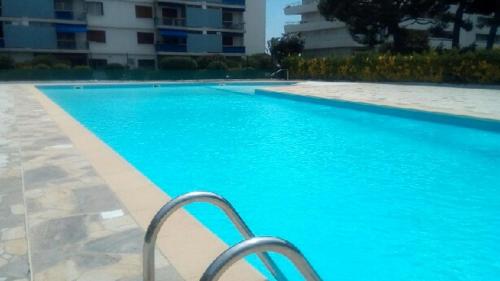 une piscine bleue avec une chaise en face d'un bâtiment dans l'établissement studio cagnes sur mer, à Cagnes-sur-Mer