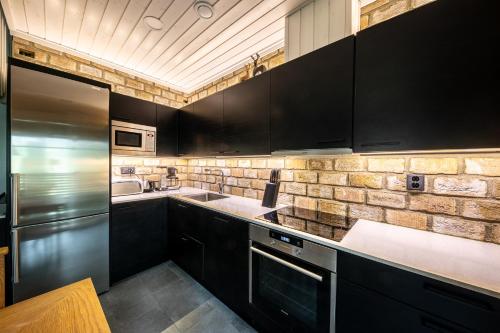 a kitchen with black cabinets and a brick wall at Hullun Mustikka Levi in Levi