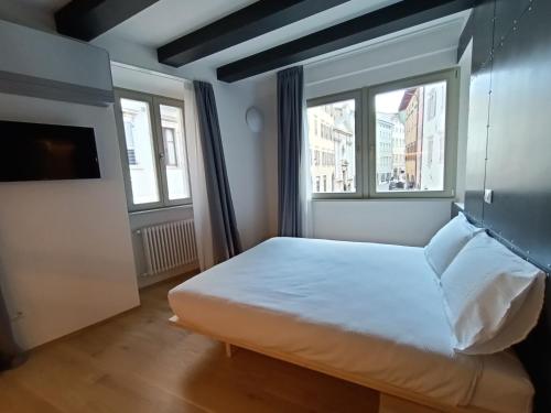 a small bedroom with a bed and two windows at Le Meridiane City Rooms In Trento in Trento