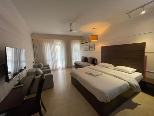 a bedroom with a bed and a couch and a television at Casa Legend Villa & Apartments Arpora - Baga - Goa in Baga