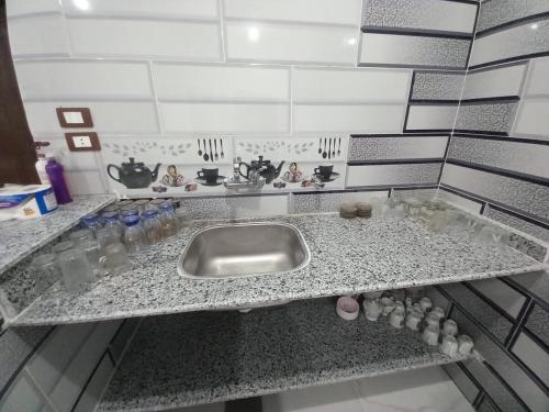 a kitchen counter with a sink and some bottles and glasses at Jamaica Guest House in Aswan