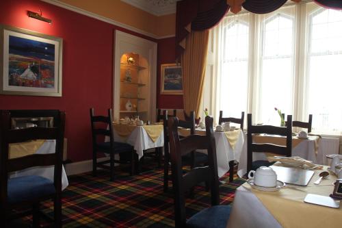 a dining room with tables and chairs and windows at Glenbervie Guest House in Oban