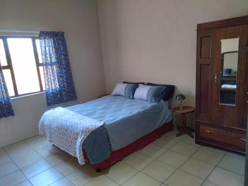 a bedroom with a bed and a dresser and a window at Non Stop Adventures in Pietermaritzburg