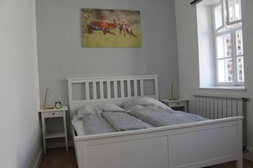a white bedroom with a bed and a picture on the wall at Zwinger Apartman in Sopron