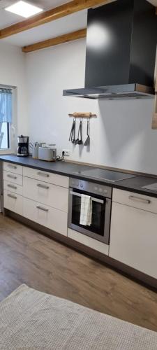 a kitchen with white cabinets and a stove top oven at Ferienwohnung Spessartbude in Schollbrunn
