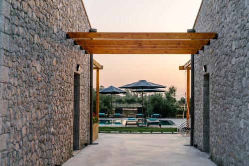 a brick wall with an archway leading to a pool at Irissa Suites in Paralía Iríon