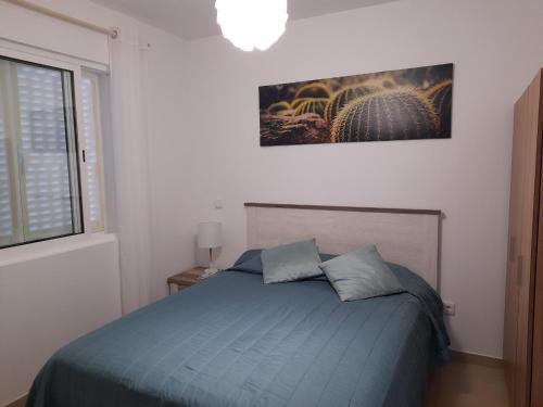 um quarto com uma cama azul e um quadro na parede em Casa Azul em Porto Santo