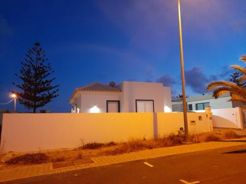 uma casa branca com uma parede amarela e uma árvore em Casa Azul em Porto Santo