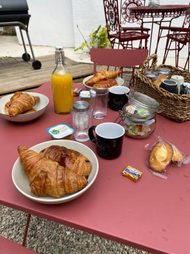 a table with bread and croissants and orange juice at Chambre Centre Ville Le Blanc in Le Blanc