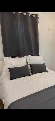 - un lit avec une tête de lit noire et des oreillers blancs dans l'établissement Appartement avec piscine privée, à Cagnes-sur-Mer