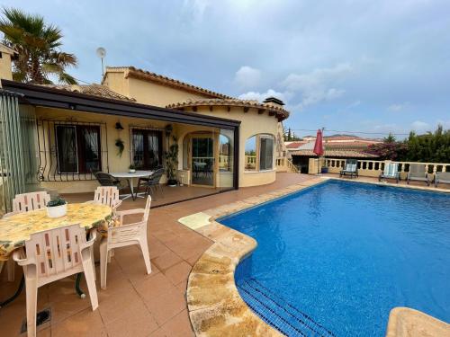 taras ze stołem i krzesłami oraz basenem w obiekcie Villa Alexandra Calpe w mieście Calpe