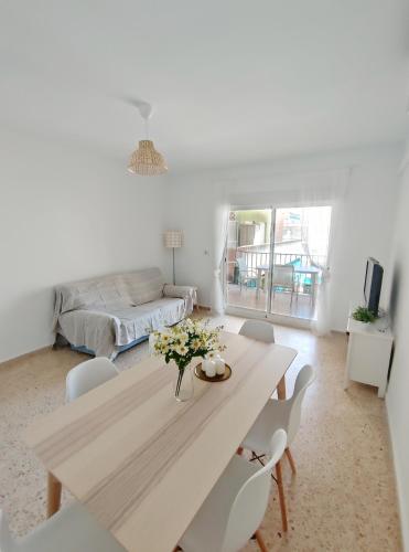 ein weißes Wohnzimmer mit einem Tisch und Stühlen in der Unterkunft Precioso apartamento en la playa de Bellreguard in Bellreguart