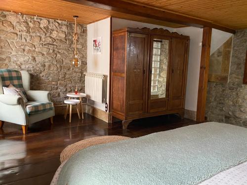 a bedroom with a bed and a cabinet and a chair at El Apartamentin - en el corazón del Parque Natural de Redes in Ríoseco