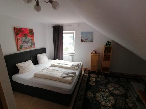 a bedroom with a bed with white sheets and a window at Zimmer in Kaiserslautern in Kaiserslautern