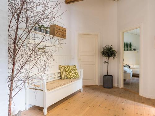 een woonkamer met een witte bank en een boom bij Cosy Retreat in Henne Strand-By Traum in Henne Strand