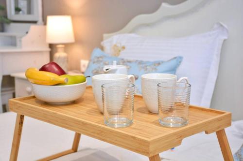 a wooden table with a bowl of fruit and glasses on it at Casa Tramonto Beach View Agios Gordios Corfu in Agios Gordios