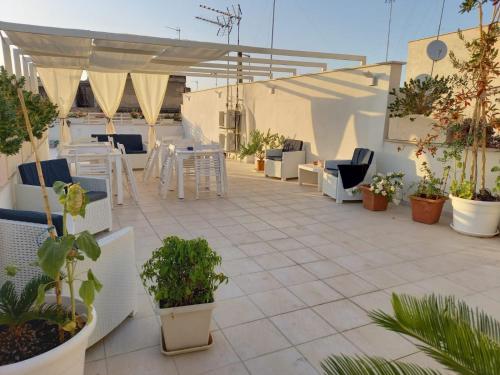 een patio met tafels en stoelen en potplanten bij B&B LA GRAZIA in Trani