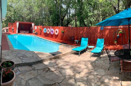 a swimming pool with blue chairs and a fence at Lamb's Rest Inn in New Braunfels