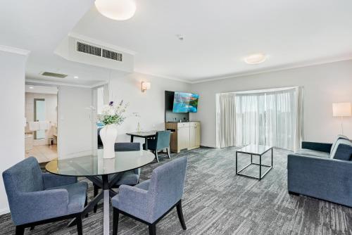 a living room with a table and chairs and a couch at Cairns Sheridan Hotel in Cairns